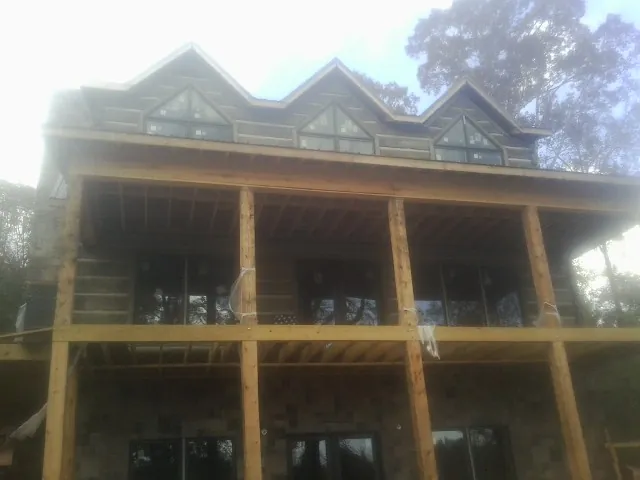 Dormers and porch framing on a large log home under construction — Roof Coating work by our crew in Silver Point