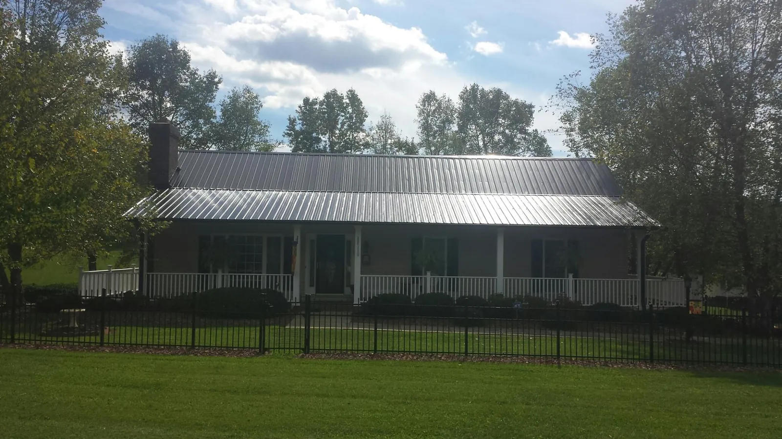 Gray metal roof on a brick ranch with a full width front porch — Gutter Guard Installation work by our crew in Silver Point