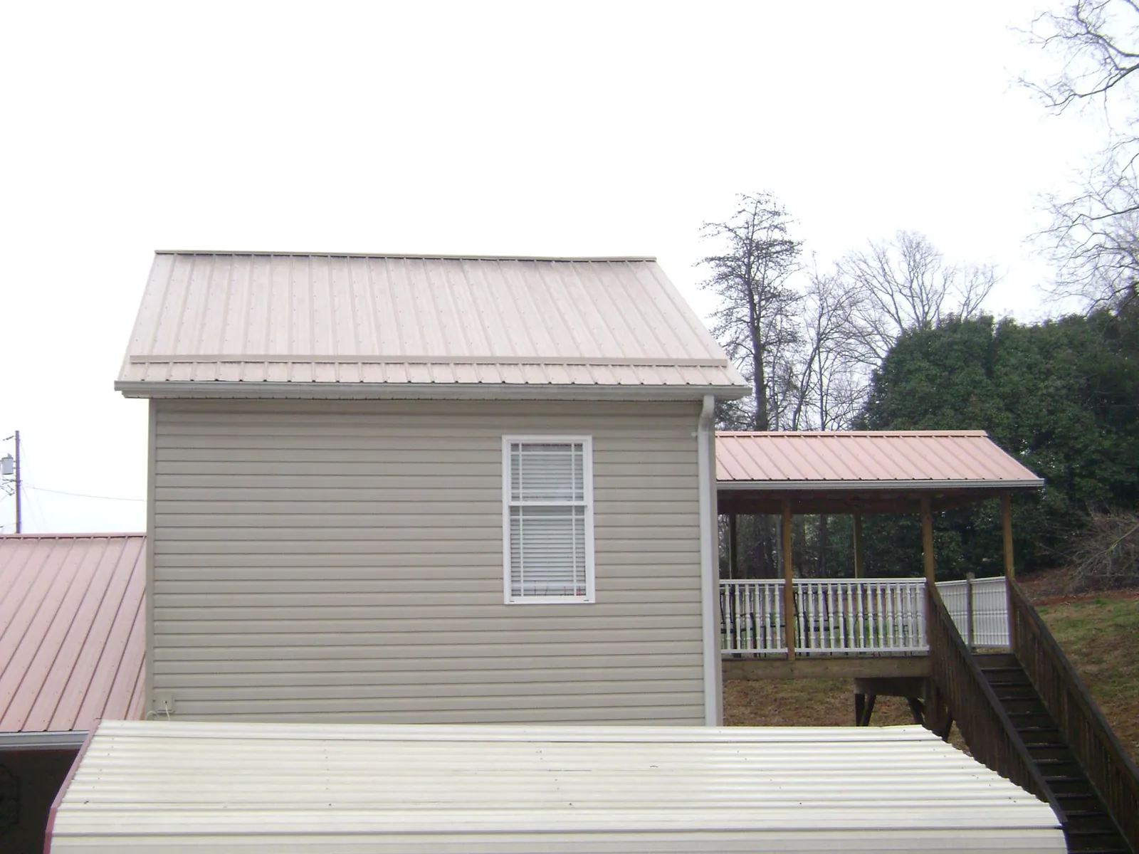 Tan metal roofs on a two story addition and attached porch, from a Roof Replacement job in Silver Point