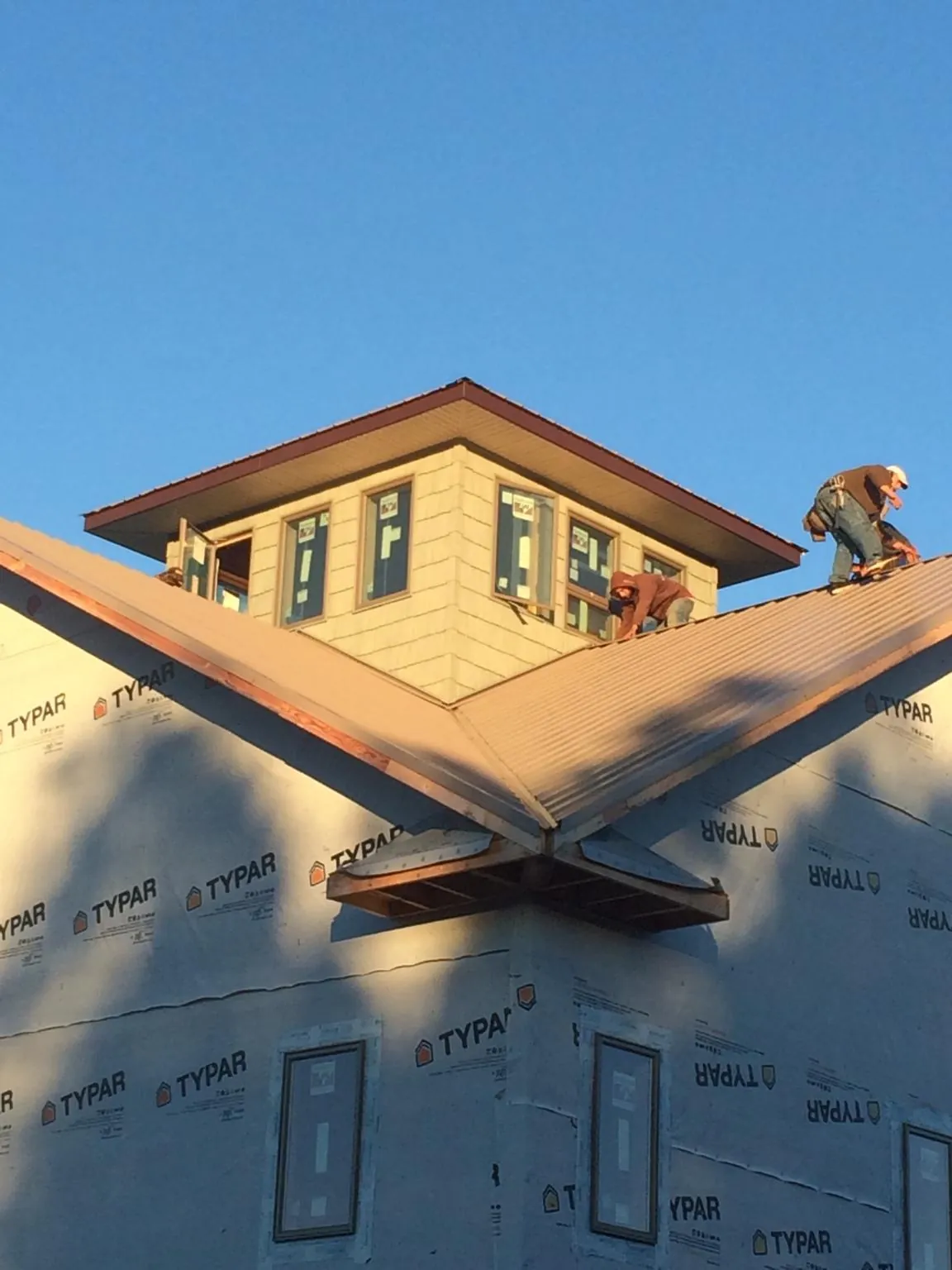 Roofers working around a rooftop cupola on a new metal roof at sunset — Roof Waterproofing in Silver Point by Roofing Brothers